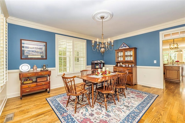 20 Jasmine Ct, Newnan, GA 30265 - dining room featuring a chandelier, plenty of natural light, light wood finished floors, crown molding, and wainscoting