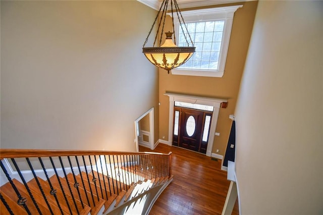 foyer featuring a towering ceiling, baseboards, and wood finished floors