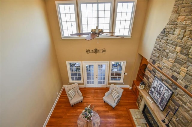 living area with french doors, a fireplace, wood finished floors, and baseboards