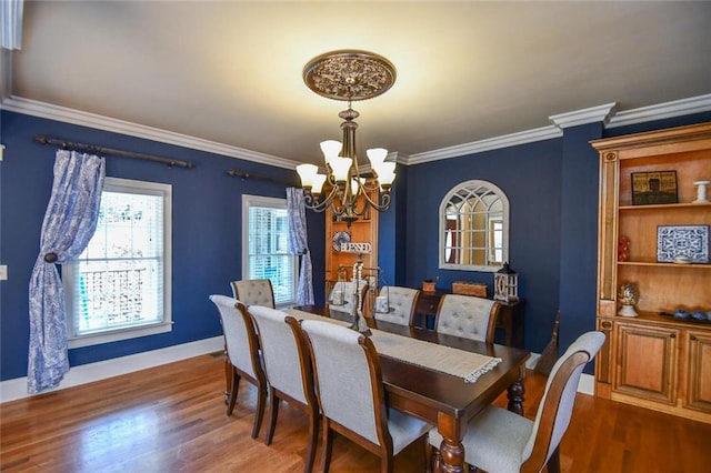 dining area featuring a chandelier, ornamental molding, wood finished floors, and baseboards