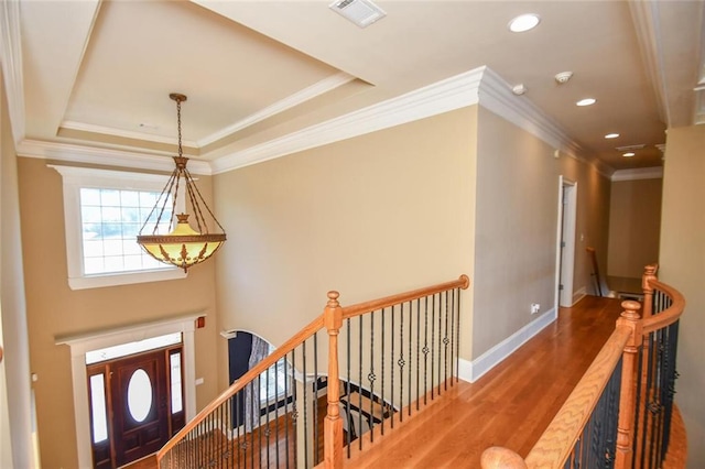 foyer entrance with a raised ceiling, wood finished floors, visible vents, and baseboards