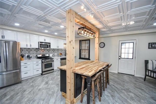 kitchen featuring baseboards, light countertops, appliances with stainless steel finishes, decorative backsplash, and an ornate ceiling