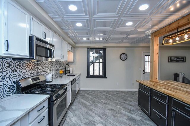 kitchen featuring an ornate ceiling, tasteful backsplash, appliances with stainless steel finishes, white cabinets, and dark cabinets