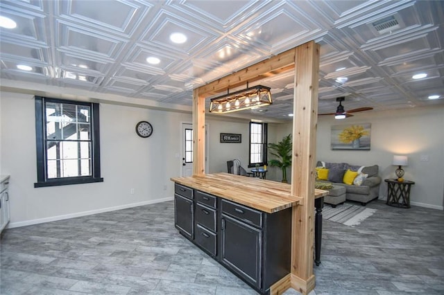 kitchen featuring an ornate ceiling, baseboards, wooden counters, and dark cabinetry