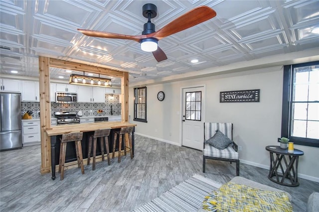 kitchen with appliances with stainless steel finishes, backsplash, butcher block counters, and an ornate ceiling