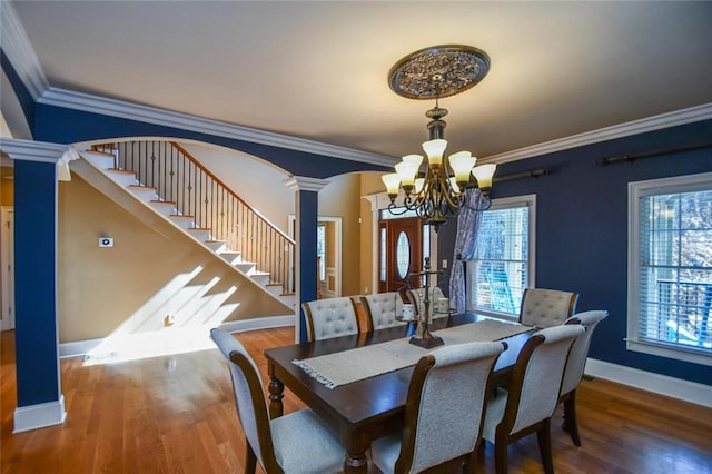 dining room featuring stairs, plenty of natural light, wood finished floors, and ornate columns