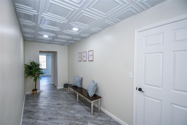 hallway with an ornate ceiling, baseboards, and wood finished floors