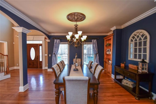 dining area with a chandelier, arched walkways, dark wood finished floors, and stairs