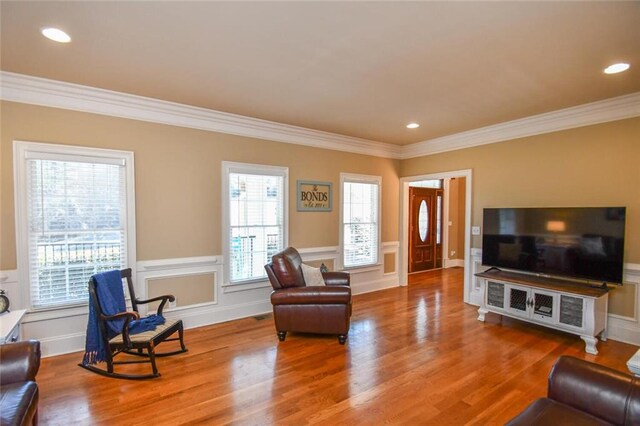 living area with a wainscoted wall, ornamental molding, wood finished floors, and recessed lighting