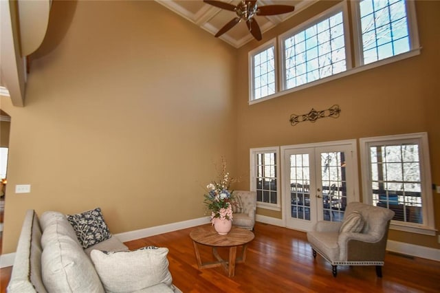 interior space featuring french doors, a towering ceiling, a ceiling fan, wood finished floors, and baseboards