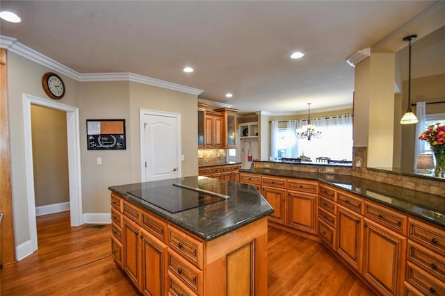 kitchen with dark wood-type flooring, black electric stovetop, brown cabinetry, and tasteful backsplash