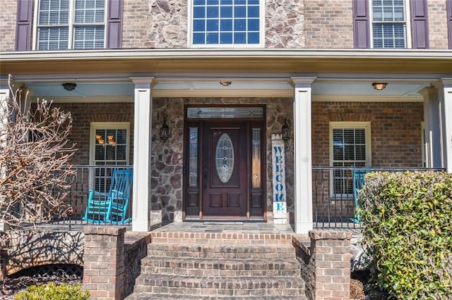 entrance to property featuring covered porch and brick siding