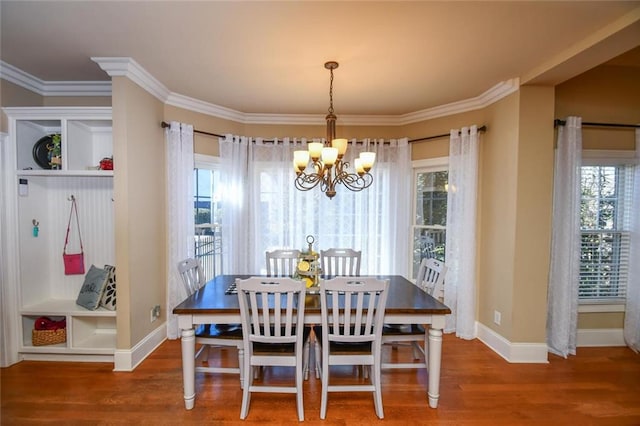 dining room with baseboards, ornamental molding, wood finished floors, and a notable chandelier