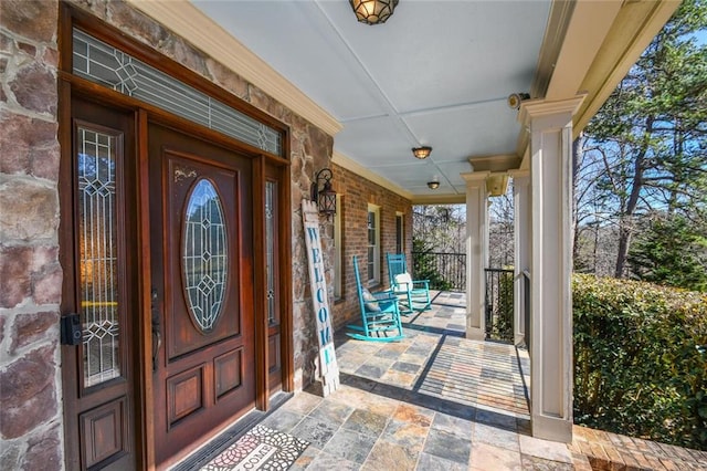 doorway to property with a porch and brick siding