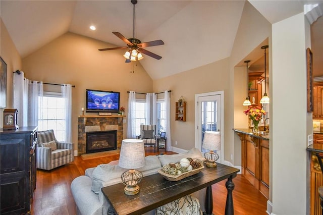 living area featuring dark wood-style flooring, a fireplace, ceiling fan, high vaulted ceiling, and baseboards