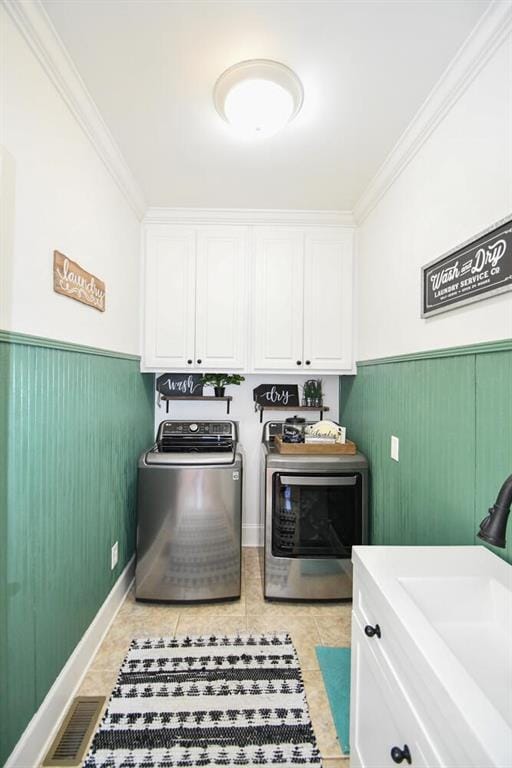 washroom with a wainscoted wall, visible vents, ornamental molding, independent washer and dryer, and cabinet space