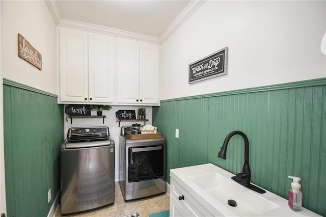 clothes washing area with cabinet space, wainscoting, ornamental molding, separate washer and dryer, and a sink