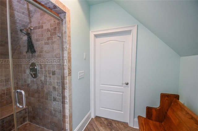 full bath featuring a stall shower, vaulted ceiling, baseboards, and wood finished floors