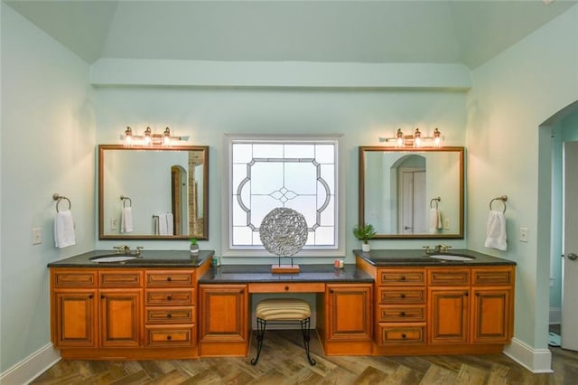 bathroom featuring a sink, baseboards, and double vanity