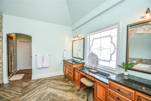 bathroom with vaulted ceiling, a shower stall, vanity, and baseboards