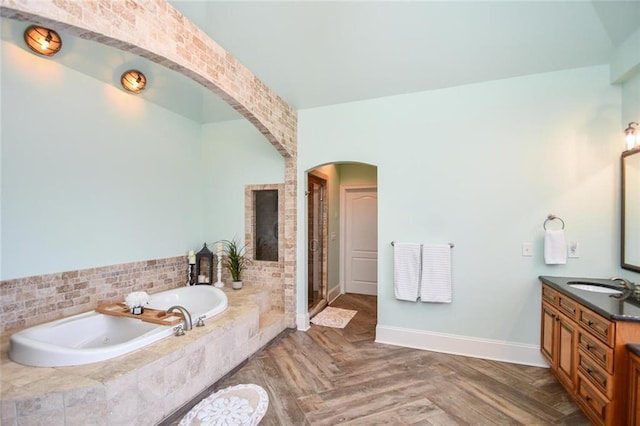 bathroom with baseboards, a garden tub, vanity, and a shower stall