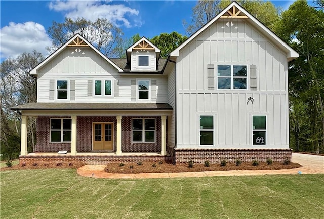 view of front of house with board and batten siding, a front lawn, a shingled roof, and brick siding
