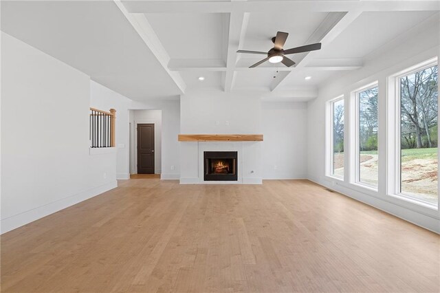 unfurnished living room featuring light wood-style flooring, coffered ceiling, beam ceiling, a ceiling fan, and baseboards