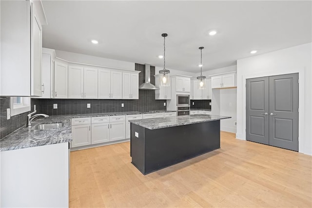 kitchen featuring appliances with stainless steel finishes, a sink, backsplash, light wood finished floors, and recessed lighting