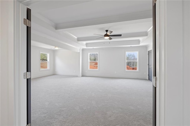 carpeted empty room with ceiling fan, a raised ceiling, and baseboards