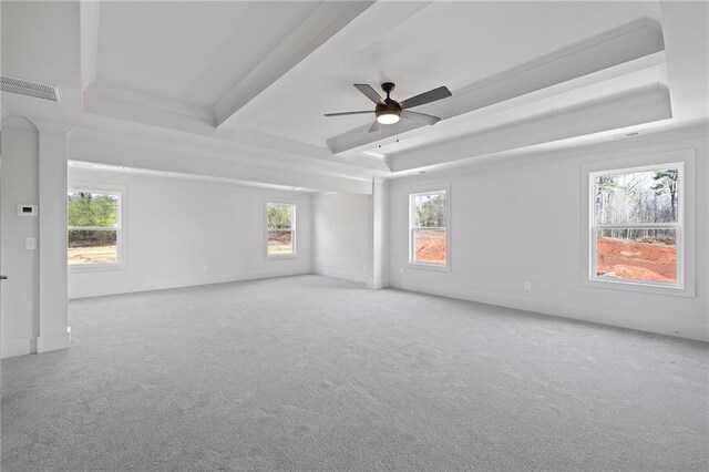 carpeted spare room featuring a tray ceiling, plenty of natural light, a ceiling fan, beamed ceiling, and baseboards