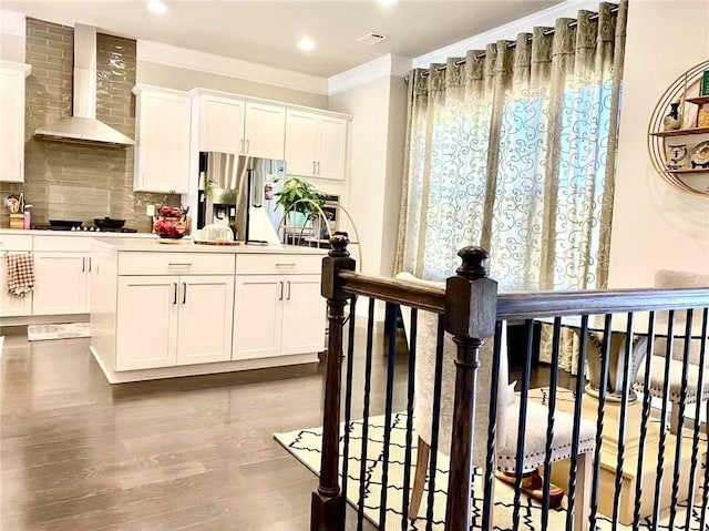 kitchen with white cabinetry, decorative backsplash, ornamental molding, stainless steel fridge with ice dispenser, and wall chimney range hood