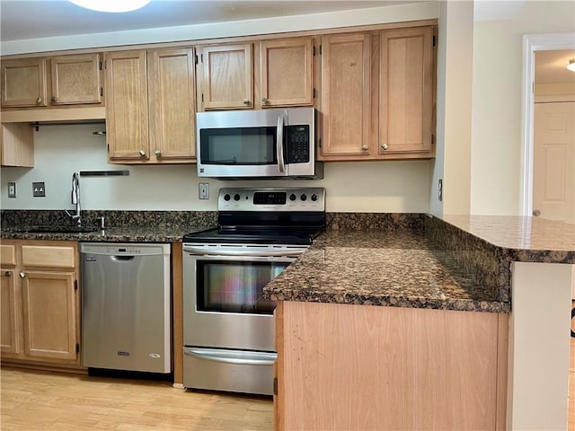 199 14th St NE Unit 710, Atlanta, GA 30309 - kitchen featuring stainless steel appliances, light wood-type flooring, a peninsula, and dark stone countertops