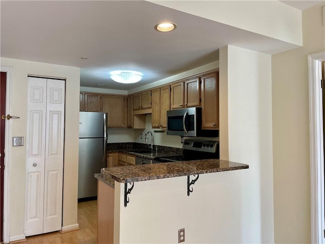 199 14th St NE Unit 710, Atlanta, GA 30309 - kitchen with stainless steel appliances, a peninsula, a kitchen breakfast bar, light wood finished floors, and recessed lighting