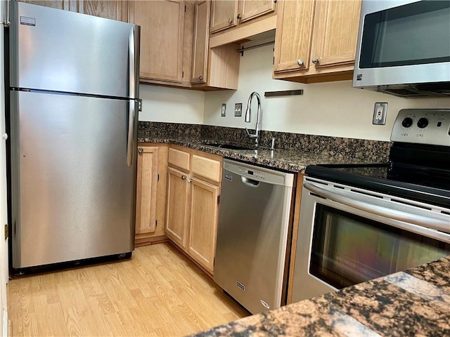 199 14th St NE Unit 710, Atlanta, GA 30309 - kitchen featuring appliances with stainless steel finishes, light wood-style flooring, dark stone counters, and light brown cabinets