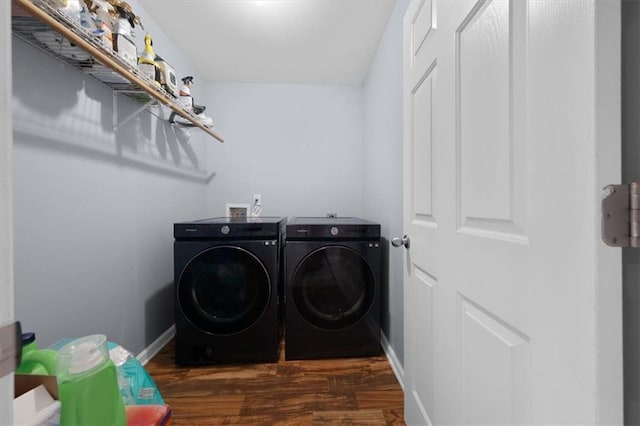 washroom featuring laundry area, washing machine and dryer, baseboards, and wood finished floors