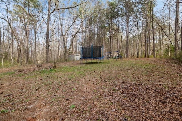 view of yard featuring an outbuilding, a shed, and a trampoline