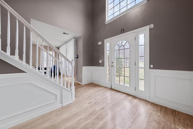 entryway with stairway, a wainscoted wall, wood finished floors, and a decorative wall