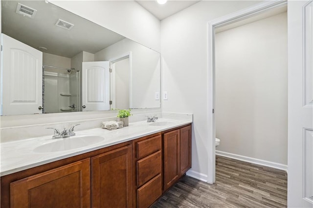 bathroom with a shower, vanity, hardwood / wood-style flooring, and toilet