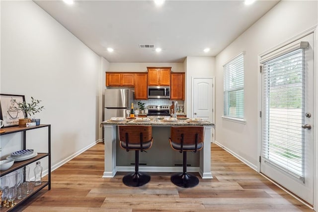 kitchen featuring a kitchen bar, a kitchen island with sink, light hardwood / wood-style flooring, and stainless steel appliances