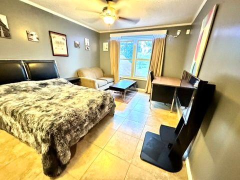 bedroom with crown molding, ceiling fan, and light tile patterned flooring