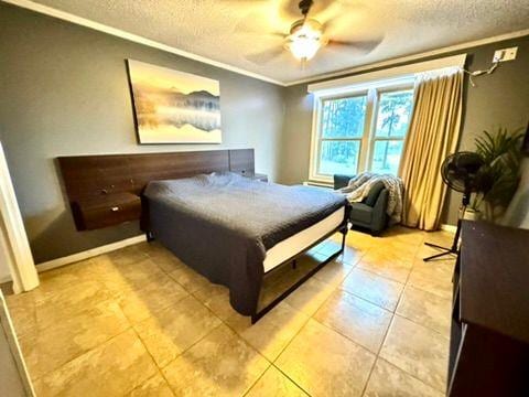 tiled bedroom with crown molding, ceiling fan, and a textured ceiling