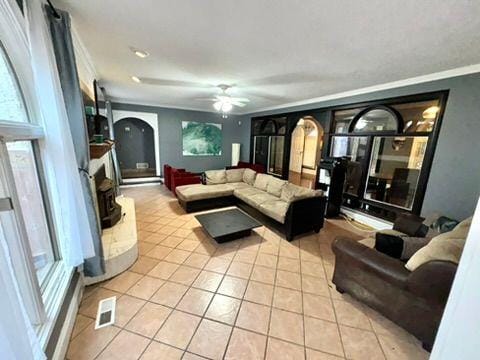 tiled living room with ornamental molding and ceiling fan