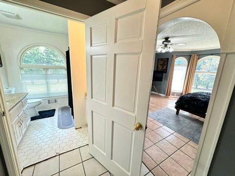 bathroom with tile patterned flooring, ceiling fan, toilet, and a healthy amount of sunlight