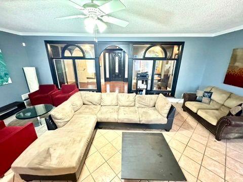 living room featuring crown molding, ceiling fan, tile patterned floors, and a textured ceiling