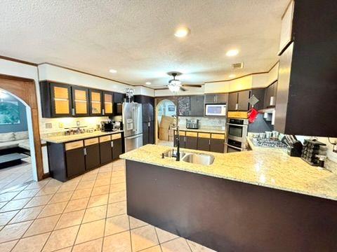 kitchen featuring sink, ceiling fan, light tile patterned flooring, stainless steel fridge with ice dispenser, and kitchen peninsula