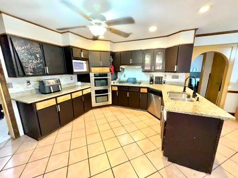 kitchen featuring sink, light tile patterned floors, dark brown cabinets, and stainless steel appliances