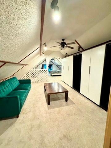 unfurnished living room featuring vaulted ceiling and ceiling fan