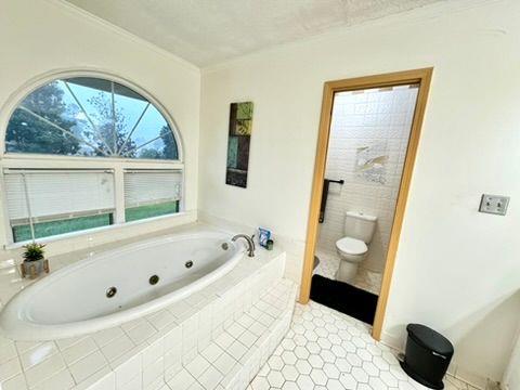 bathroom with ornamental molding, toilet, tile patterned flooring, and tiled bath