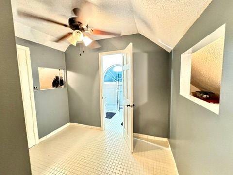 interior space with ceiling fan, vaulted ceiling, and a textured ceiling