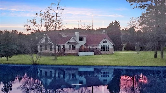 back house at dusk featuring a lawn